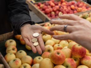 Personen räcker en annan mynt över affärens äppelverk.